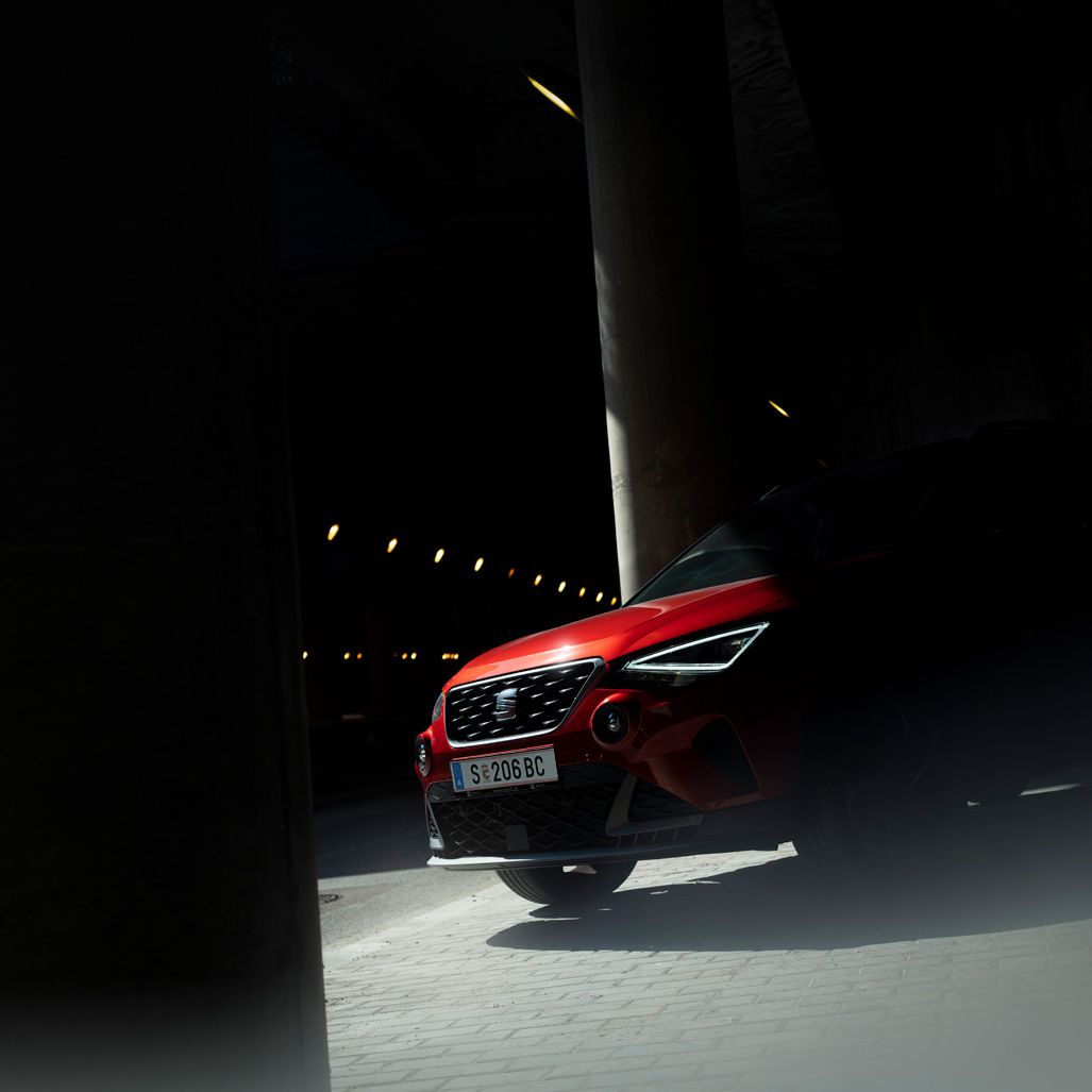 Fahrzeugaufnahme eines SEAT Arona, dessen Motorhaube von Licht getroffen wird und der Rest im Schatten bleibt.