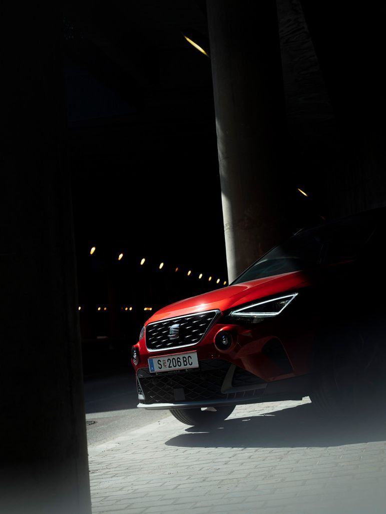 Fahrzeugaufnahme eines SEAT Arona, dessen Motorhaube von Licht getroffen wird und der Rest im Schatten bleibt.